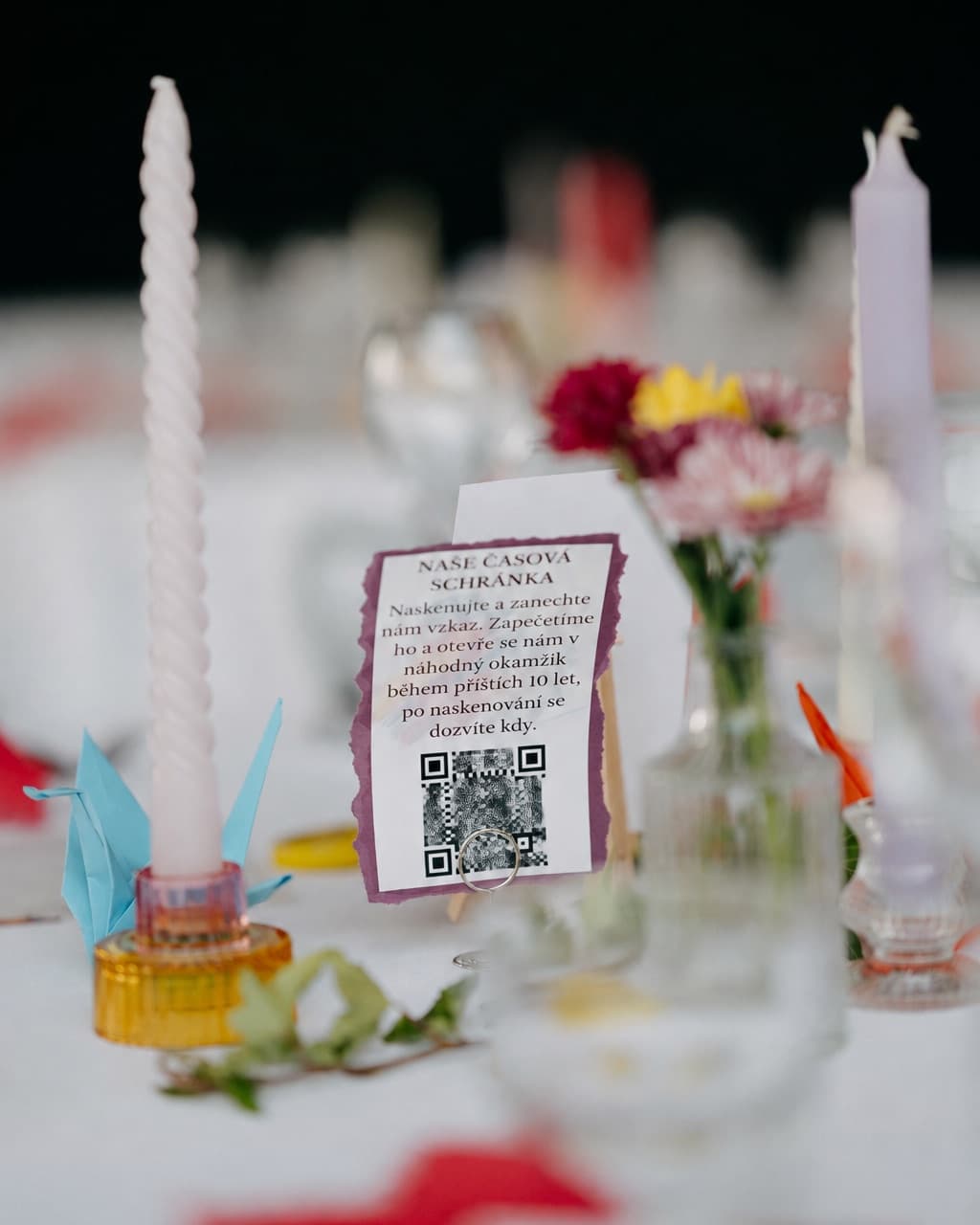 Kartička s QR kódom na svadobnom stole medzi sviečkami a kvetmi